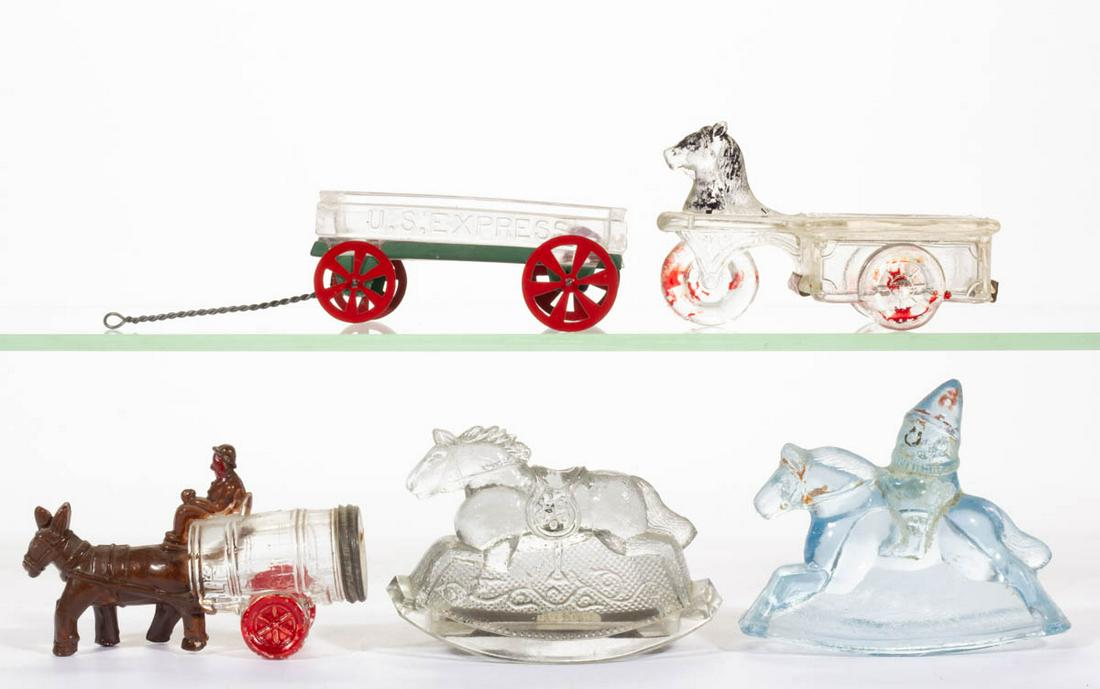 ASSORTED FIGURAL HORSE AND BUGGY GLASS CANDY: ASSORTED FIGURAL HORSE AND BUGGY GLASS CANDY CONTAINERS, LOT OF FIVE, colorless and blue, including a Mule Pulling Two Wheeled Barrel with Driver, a Rocking Horse, and a Rocking Horse with Clown Rider