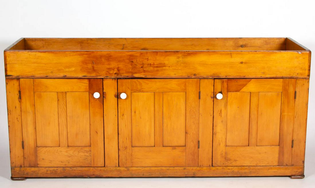 AMERICAN COUNTRY PINE DRY SINK: AMERICAN COUNTRY PINE DRY SINK, rectangular well above three double-fielded-panel doors with later porcelain knobs, solid ends, raised on simple applied feet. Old refinished surface with mellow color.