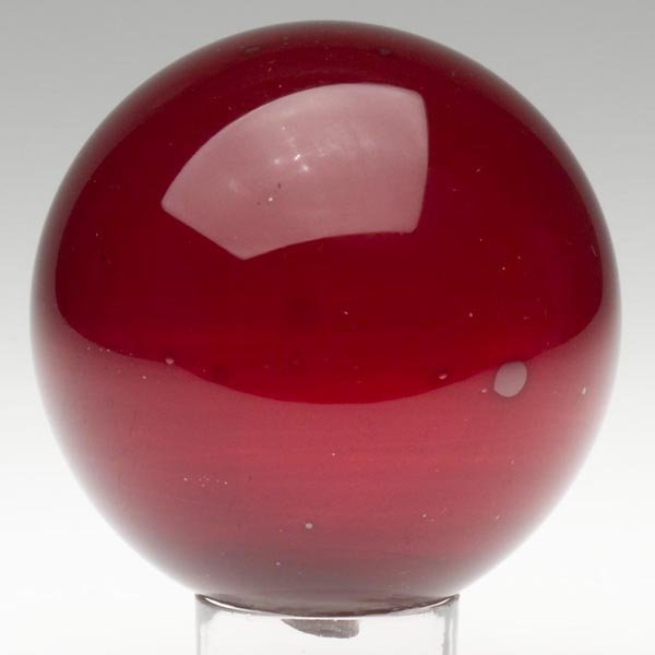 FREE-BLOWN WITCH BALL: FREE-BLOWN WITCH BALL, cased deep ruby, rough pontil mark with a 1/2 in. opening. Boston & Sandwich Glass Co. and others. 1850-1880. Diameter: 4 3/4 in. Literature: Parallels B & K III, figs. 3225-323