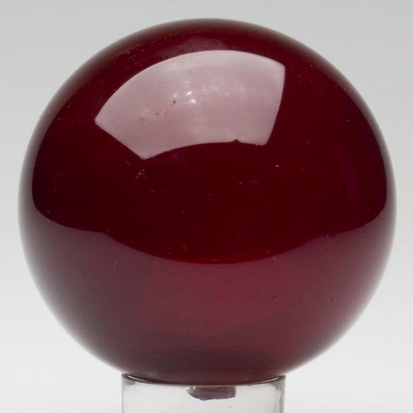 FREE-BLOWN WITCH BALL: FREE-BLOWN WITCH BALL, deep ruby, rough pontil mark with a 3/8 in. opening. United States. 1850-1880. Diameter: 4 3/4 in. Literature: Parallels B & K III, figs. 3225-3233.