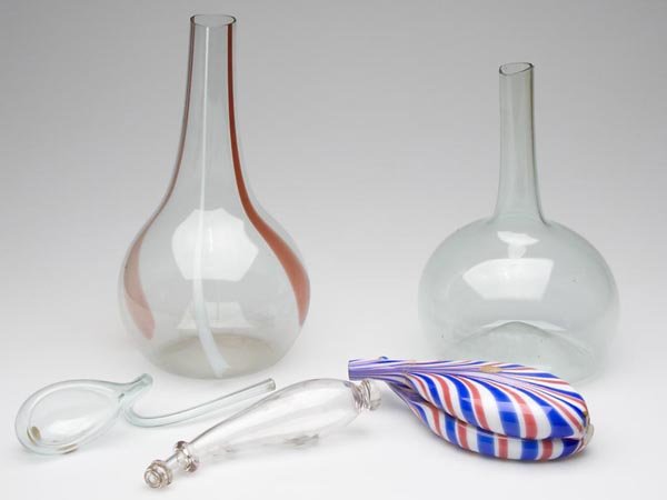FIVE ASSORTED FREE-BLOWN WHIMSIES: FIVE ASSORTED FREE-BLOWN WHIMSIES, comprised of a colorless powder horn with powder stains, a light green dipper with an old label inscribed "Cleveland, N.Y. glass", two large bottles, each with a bro