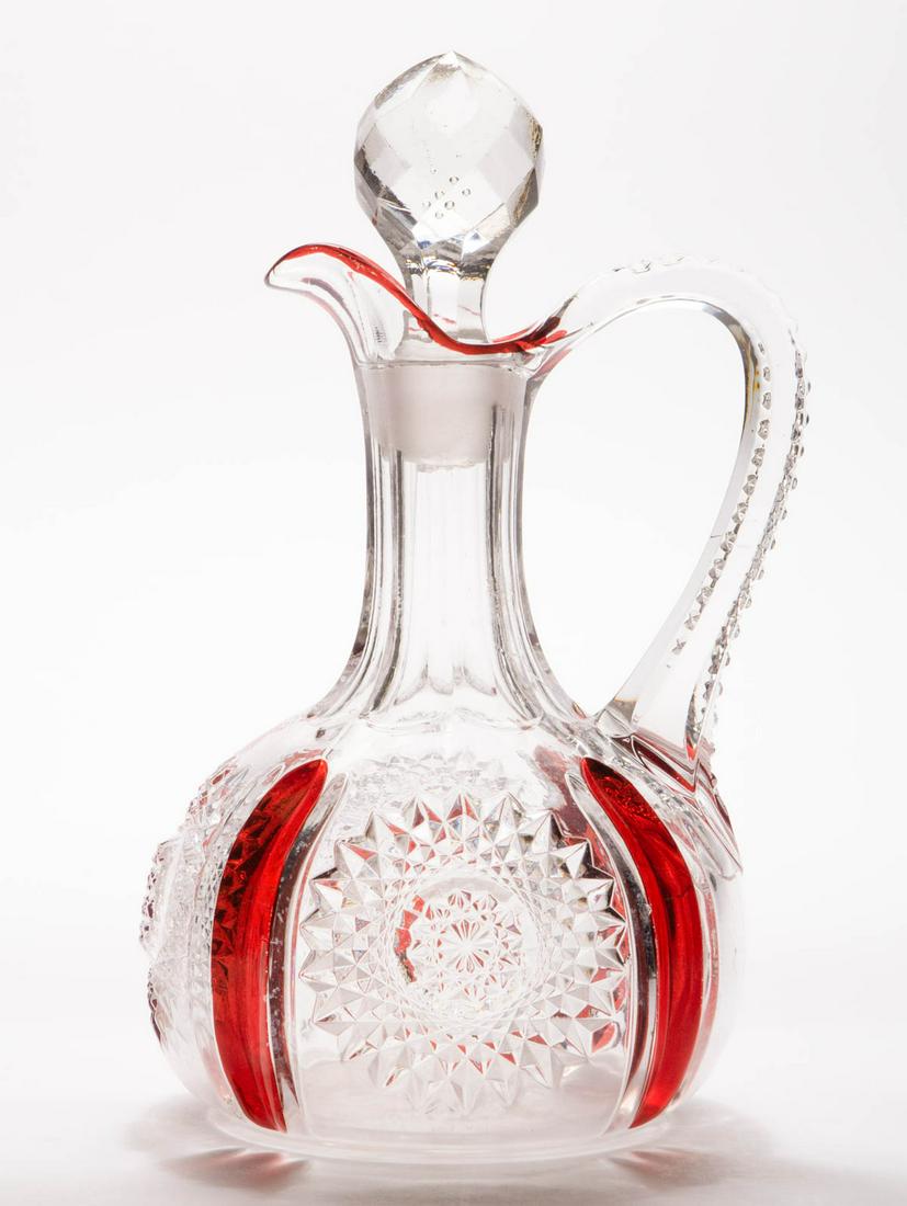 HEISEY NO. 1235 / BEAD PANEL AND SUNBURST -: HEISEY NO. 1235 / BEAD PANEL AND SUNBURST - RUBY-STAINED EWER, colorless, cut-facet stopper that is slightly ill-fitting, cut-and-shut mark under the base. A. H. Heisey & Co. Circa 1897. 9 1/2" HOA.