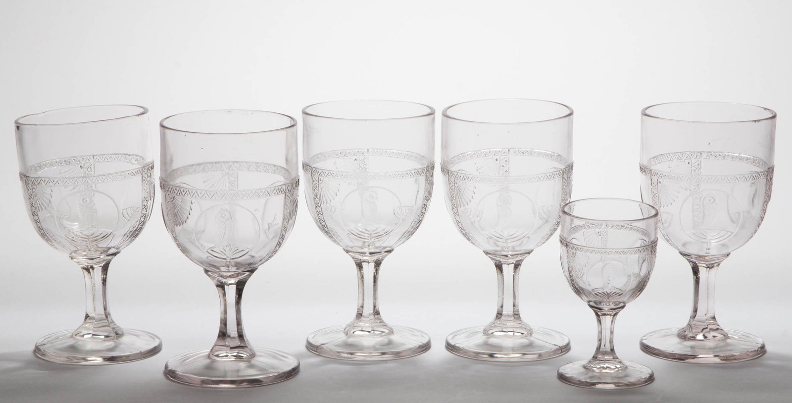 OWL IN FAN / PARROT DRINKING ARTICLES, LOT OF SIX: OWL IN FAN / PARROT DRINKING ARTICLES, LOT OF SIX, colorless, comprising five goblets and a wine, one goblet having a bird and bee. Fourth quarter 19th century. Goblets: 5 1/2" H. Wine: 3 7/8" H. Prov