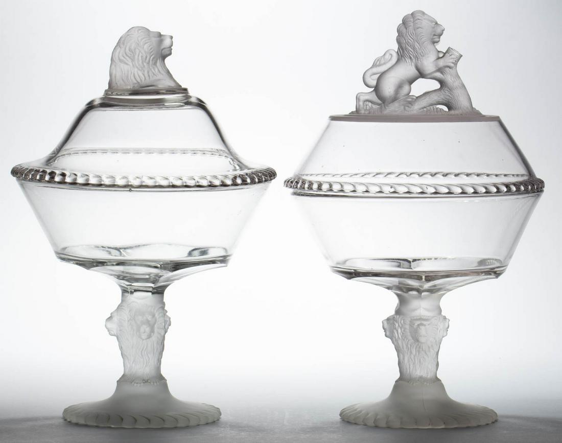 LION - FROSTED COVERED COMPOTES, LOT OF TWO: LION - FROSTED COVERED COMPOTES, LOT OF TWO, colorless and frosted, each on a high standard with lion heads, one having a lion head finial, other with a rampant lion finial. Gillinder & Sons, Philadel