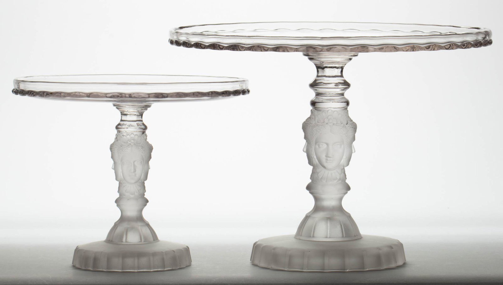 THREE FACE / DUNCAN NO. 400 (OMN) SALVERS / CAKE: THREE FACE / DUNCAN NO. 400 (OMN) SALVERS / CAKE STANDS, LOT OF TWO, colorless and frosted. Geo. Duncan & Sons, Pittsburgh, PA. 1878-1886. 6 3/8" and 8 1/8" H, 8" and 11" D rims. Literature: Bredehoft