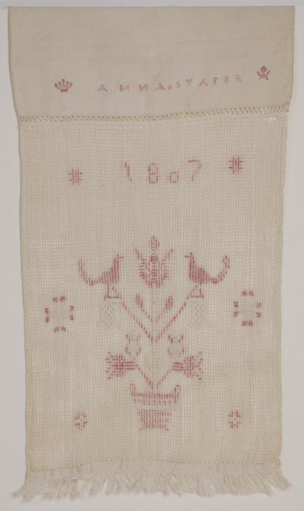 ANNA STAFER, 1807 NEEDLEWORK SHOW TOWEL: ANNA STAFER, 1807 NEEDLEWORK SHOW TOWEL, linen and cotton, needlework embellishments include name, date, and a bird tree, fringe to lower edge. Probably Pennsylvania. First quarter 19th century. 66" x