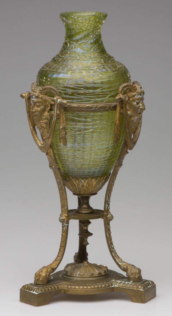 LOETZ CHINE GLASS METAL-MOUNTED VASE: LOETZ CHINE GLASS METAL-MOUNTED VASE, iridescent green with random applied threading, bolted in a neo-classical style gilt-bronze stand with satyr masks, swags, and hoof feet. Fourth quarter 19th cent