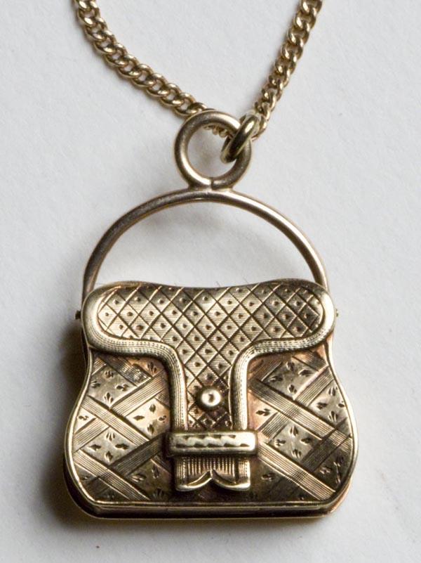 TESTED 10K GOLD LOCKET ON GOLD-FILLED CHAIN: TESTED 10K GOLD LOCKET ON GOLD-FILLED CHAIN, intricately decorated purse/satchel opens to reveal holders for two photos, unmarked. Fourth quarter 19th century. Purse 7/8" h overall, 3/4" wide, chain 2