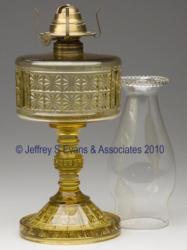 THREE PANELED TWO PANEL STAND LAMP: THREE PANELED TWO PANEL STAND LAMP, amber, No. 1 Taplin-Brown collar, period slip burner and chimney. Richards & Hartley Flint Glass Co. 9" h to top of collar, 4 5/8" dia base.Literature: Lamp as Thur