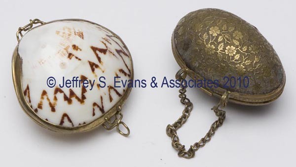 VARIOUS MATERIALS FIGURAL THIMBLE CASES, LOT OF TW: VARIOUS MATERIALS FIGURAL THIMBLE CASES, LOT OF TWO, consisting of a cowrie shell; and a brass egg form with floral decoration and chain, interior with a replaced pink fabric and brown velvet. Late 19