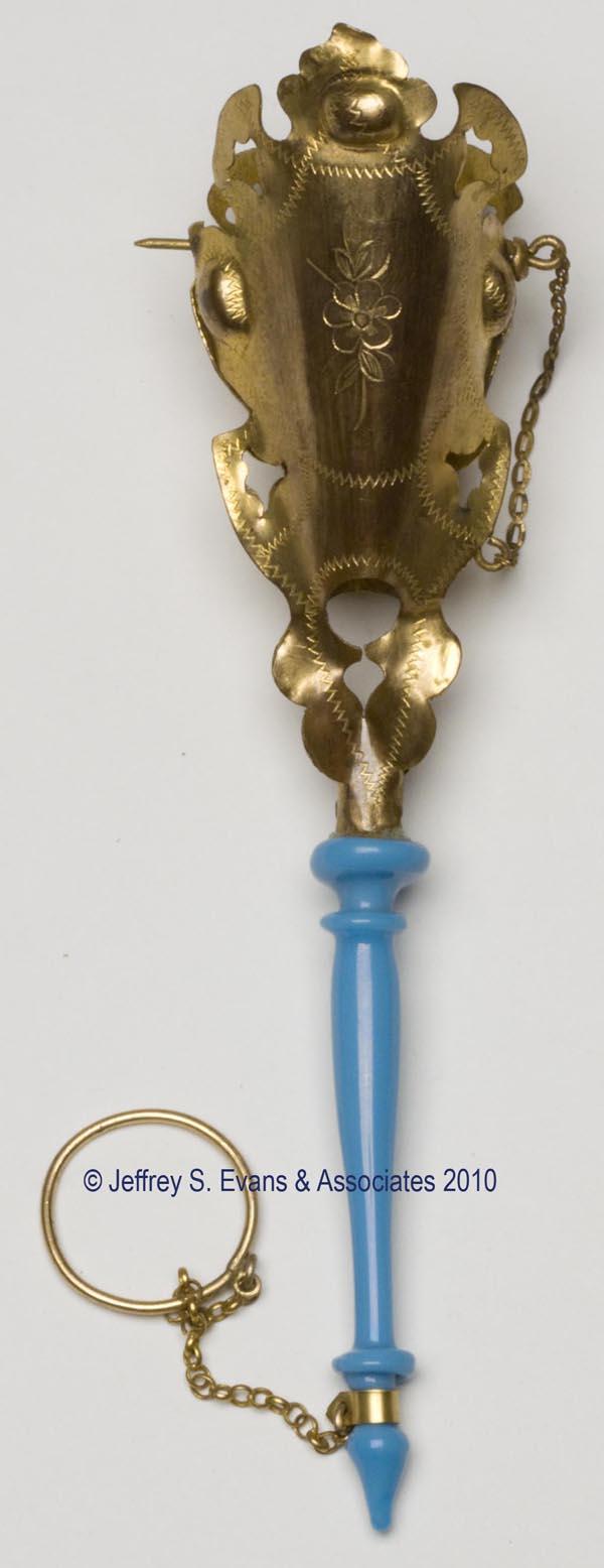 VICTORIAN GILT-BRASS TUSSIE MUSSIE POSEY HOLDER: VICTORIAN GILT-BRASS TUSSIE MUSSIE POSEY HOLDER, stamped and engraved decorations, opaque blue glass handle, chains suspending securing spike and finger ring. 19th century. 6" h. Provenance: Hilda Fri