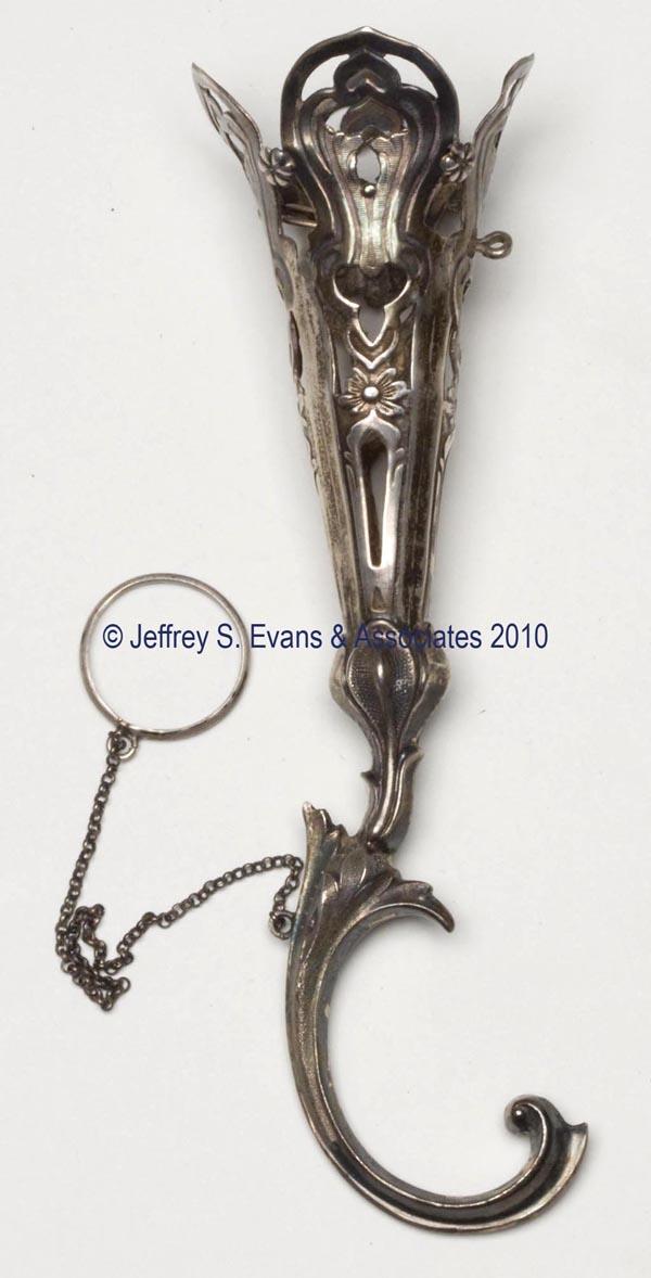 VICTORIAN PLATED-SILVER TUSSIE MUSSIE POSEY HOLDER: VICTORIAN PLATED-SILVER TUSSIE MUSSIE POSEY HOLDER, stamped and engraved foliate and scroll decorations, chain suspending finger ring, cotter-pin-style securing pin without chain. 19th century. 5" h. 