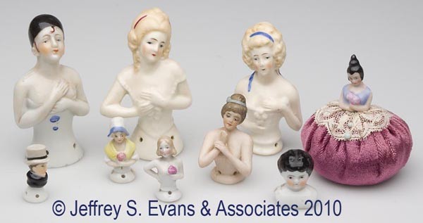 NINE ASSORTED CHINA HALF DOLLS: NINE ASSORTED CHINA HALF DOLLS, several marked Germany, one marked Japan, one fitted on a contemporary pin cushion. First half 20th century. 1 1/4" to 3 3/4" h. Provenance: Collection of the late Fern