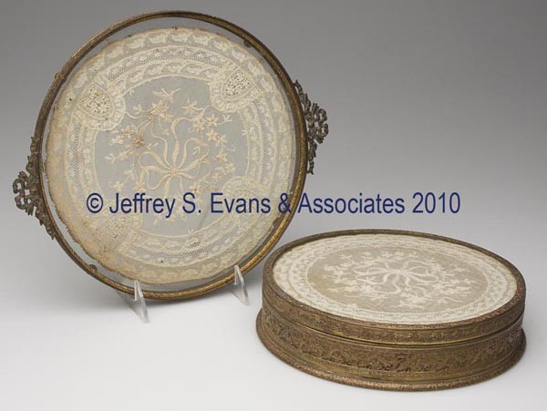 TWO GILT-BRASS AND GLASS DRESSER ARTICLES: TWO GILT-BRASS AND GLASS DRESSER ARTICLES, comprised of a tray and matching covered box, both set with a lace doily, box with glass divided insert and marked "EMPIRE ART GOLD" under the base. First ha