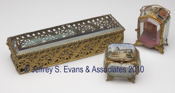 THREE GILT-METAL AND BEVELED-GLASS JEWEL CASKETS: THREE GILT-METAL AND BEVELED-GLASS JEWEL CASKETS, comprised of an upright example with bail handle, a low example with the US Capitol reverse painted on lid, and a long rectangular example. Late 19th/