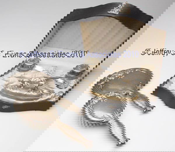 WEBSTER STERLING SILVER TWO-PIECE TOILET SET: WEBSTER STERLING SILVER TWO-PIECE TOILET SET, comprised of a hand mirror and brush, each with floral ornamentation. Along with a six-piece silver-plated dresser set in a fitted box. Eight pieces total