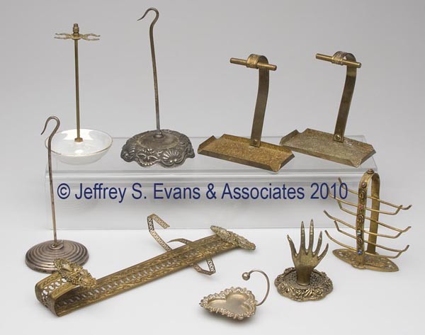 NINE ASSORTED RACKS / STANDS: NINE ASSORTED RACKS / STANDS, including sterling silver (1), silver-plate, brass, and ceramic examples. 19th and 20th centuries. Various sizes. Provenance: Hilda Fried estate, New York City.