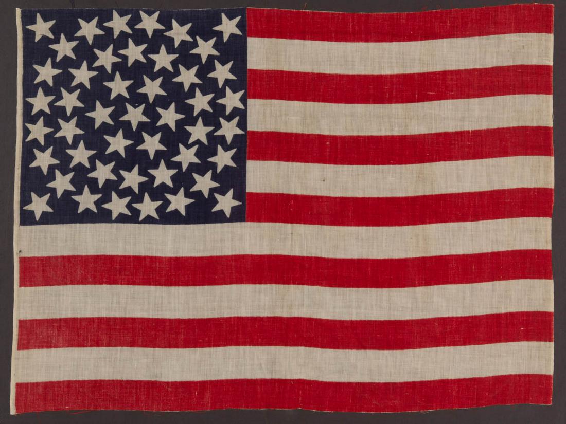 45-STAR AMERICAN NATIONAL PARADE FLAG: 45-STAR AMERICAN NATIONAL PARADE FLAG, printed cotton, canton with rare "Global" or "Triple Wreath" pattern on a dark blue ground, fly with 13 red and white stripes. Conservation mounted in a custom f