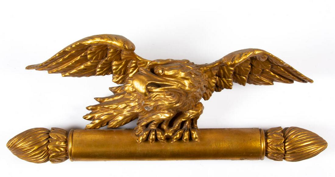 AMERICAN CARVED GILTWOOD ARCHITECTURAL PEDIMENT: AMERICAN CARVED GILTWOOD ARCHITECTURAL PEDIMENT, depicting a spread-wing eagle situated on a bar with shaped finials. Probably from a mirror. 19th century. 11" HOA, 24 1/4" WOA. Provenance: From a Sou