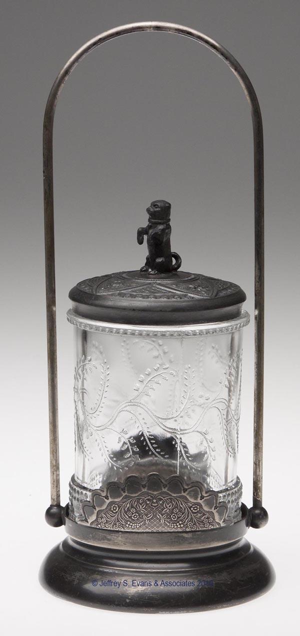 BARLEY PICKLE CASTER: BARLEY PICKLE CASTER, colorless, fitted in a Wilcox Silver Plate Co. stand, lid with dog finial. 10 1/4" h overall, 4 3/8" dia overall. Provenance: From a Vermont collection.
