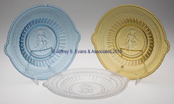 CUPID AND VENUS TAB-HANDLE PLATES, LOT OF THREE: CUPID AND VENUS TAB-HANDLE PLATES, LOT OF THREE, amber, blue and colorless. 10 1/2" dia. Provenance: From the Collection of Mrs. Elizabeth R. Clatterbuck.