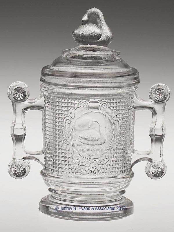 SWAN / NETTED SWAN COVERED PICKLE JAR: SWAN / NETTED SWAN COVERED PICKLE JAR, colorless, swan finial, "PAT. APPLIED FOR" under base. 6 1/2" h overall, 3 1/8" dia. Provenance: Collection of Larry and Sandy Mackle.