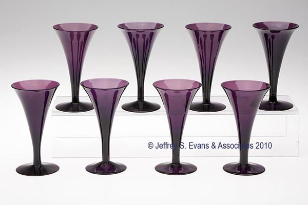 SET OF SEVEN FREE-BLOWN WINE GLASSES: SET OF SEVEN FREE-BLOWN WINE GLASSES, medium amethyst, each featuring a drawn trumpet-form bowl raised on a circular foot with a rough pontil mark. Probably England. Probably 20th century. 4 7/8" to 5