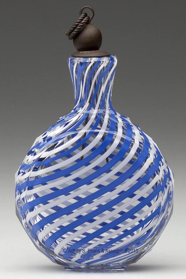 LATTICINO STRIPE COLOGNE FLASK: LATTICINO STRIPE COLOGNE FLASK, colorless with blue and white swirled threads, flattened circular form with vesica-cut sides and a panel-cut neck, period brass stopper of unknown association. Probably