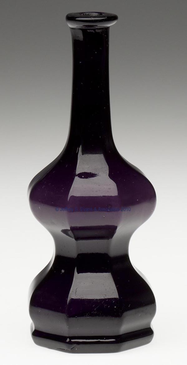 BLOWN-MOLDED PANELED COMMERCIAL COLOGNE BOTTLE: BLOWN-MOLDED PANELED COMMERCIAL COLOGNE BOTTLE, deep amethyst, deeply waisted eight-panel form with a tooled lip and plain base. Boston & Sandwich Glass Co. 1845-1870. 5 1/2" H, 2 1/4" DOA base. Liter