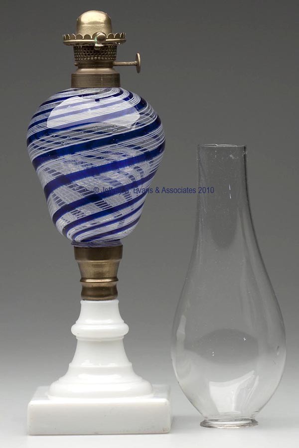 LATTICINIO (STRIPER) FONT STAND LAMP: LATTICINIO (STRIPER) FONT STAND LAMP, inverted pyriform font displaying swirling wide blue stripes alternating with groups of five white threads, raised on a brass connector and an opaque white square