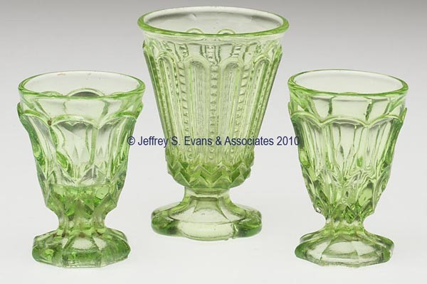 THREE ASSORTED PRESSED TOY FOOTED TUMBLERS / SPOON: THREE ASSORTED PRESSED TOY FOOTED TUMBLERS / SPOONERS, bright yellow green/vaseline, comprising a pair with a honeycomb-type pattern and raised on an octagonal foot, one with a rough pontil mark, and 