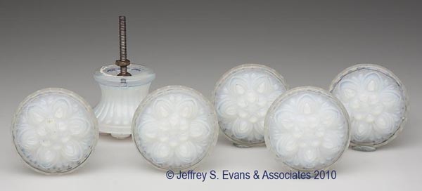 SET OF SIX PRESSED ROSETTE FURNITURE KNOBS: SET OF SIX PRESSED ROSETTE FURNITURE KNOBS, deep fiery opalescent, each face featuring six petals surrounding a central bloom, each back with an appropriate, but non-original threaded mounting bolt. B