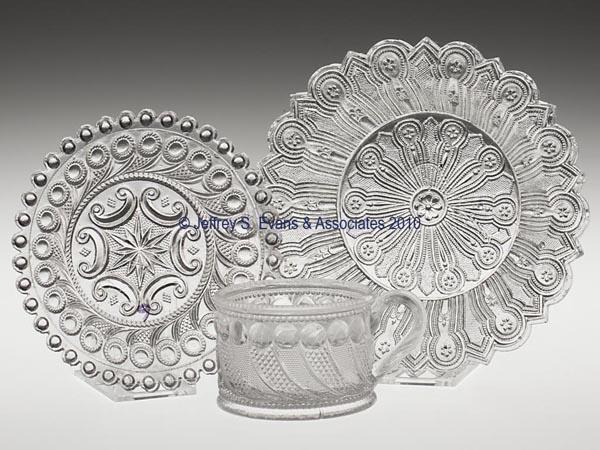 THREE ASSORTED PRESSED LACY TABLE ARTICLES: THREE ASSORTED PRESSED LACY TABLE ARTICLES, colorless, comprising a Hairpin dish, a Peacock Eye mustard cup, and a Peacock Eye with bull's-eye rim plate. Boston & Sandwich Glass Co. and Midwestern. 18