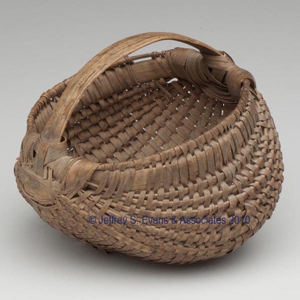 VIRGINIA WHITE OAK SPLINT RIB-TYPE DIMINUTIVE BASKE: VIRGINIA WHITE OAK SPLINT RIB-TYPE DIMINUTIVE BASKET kidney form with a wrapped double rim, bold handle-rim supports, and low arched handle. Original dry natural surface. Probably Greene/Madison Co. a