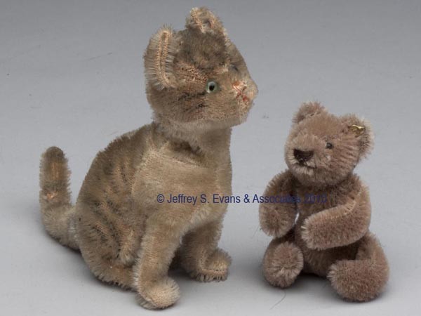 TWO STEIFF MOHAIR ANIMALS: TWO STEIFF MOHAIR ANIMALS comprising a miniature jointed Teddy Bear with brass button in ear, and a mechanical seated cat, when the tail is turned the head moves, tin button in ear. 20th century. 3" a