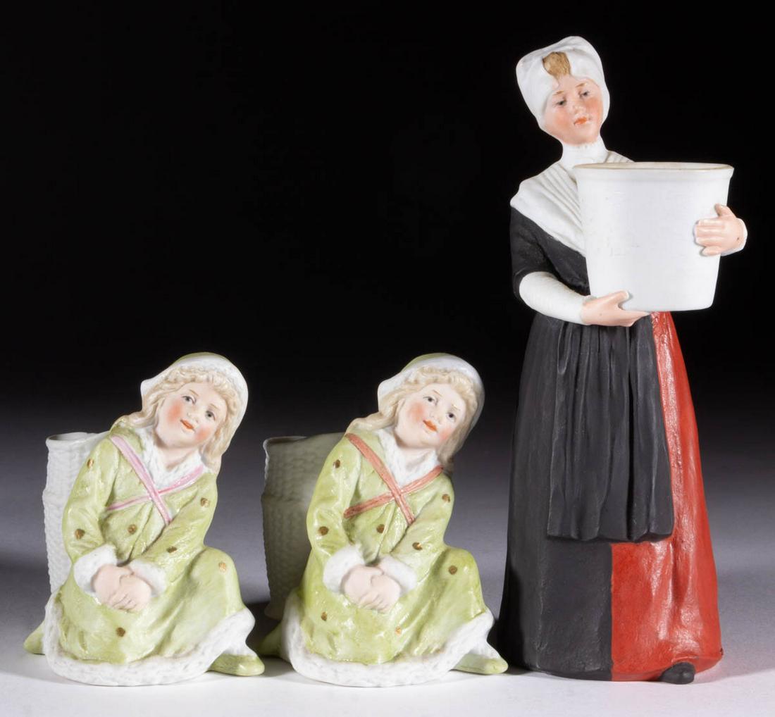 GERMAN GEBRUDER HEUBACH BISQUE PORCELAIN FIGURAL: GERMAN GEBRUDER HEUBACH BISQUE PORCELAIN FIGURAL TOOTHPICK HOLDERS, LOT OF THREE, each having polychrome hand-painted decorations, comprising two kneeling girls wearing fur-lined winter coats and open