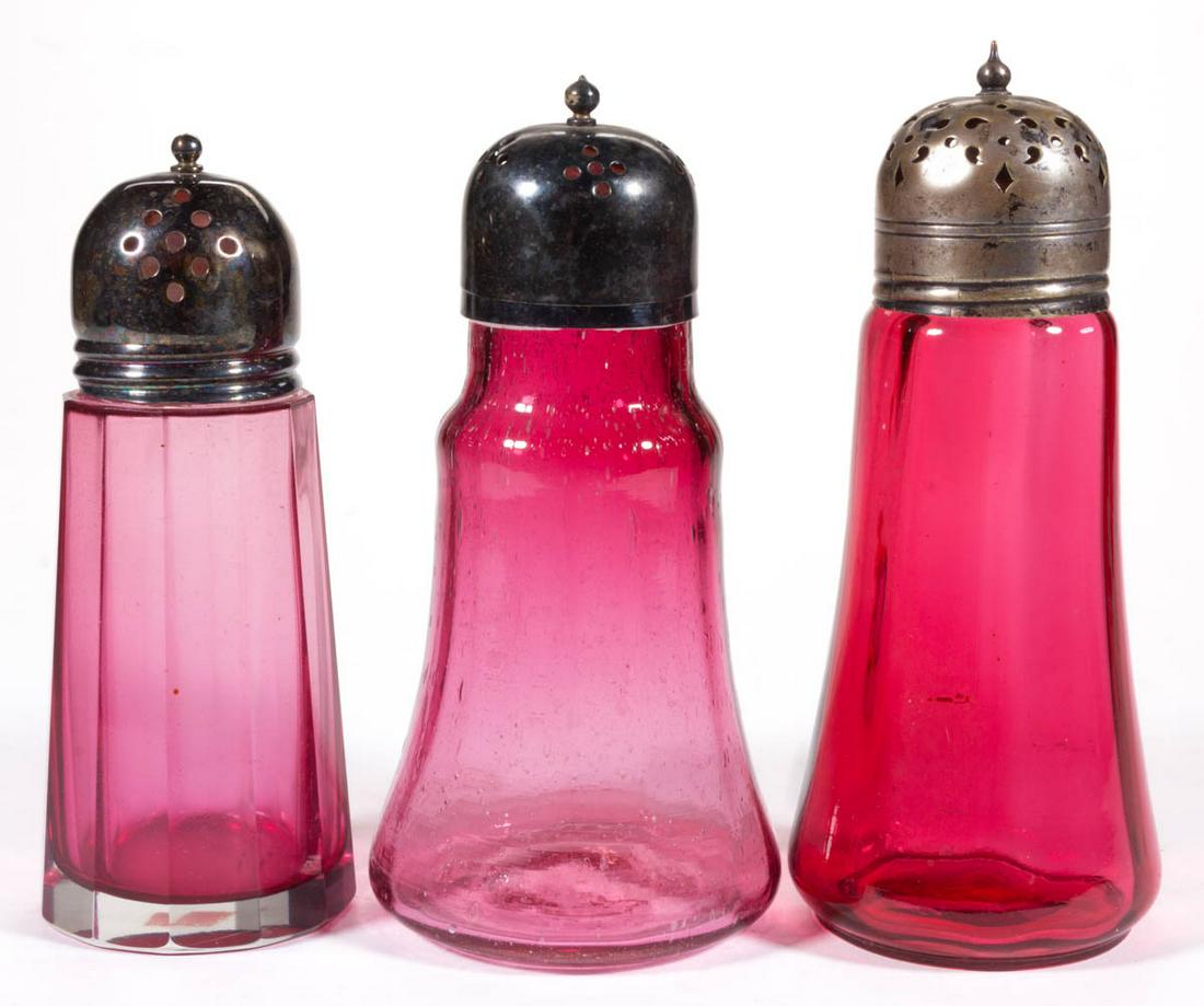 VICTORIAN CRANBERRY GLASS SUGAR SHAKERS, LOT OF THREE: VICTORIAN CRANBERRY GLASS SUGAR SHAKERS, LOT OF THREE, comprising two Panel-Optic and a cased 12-panel example, each having a period lid. Various makers. Late 19th/early 20th century. 5 3/4" to 6 1/2"