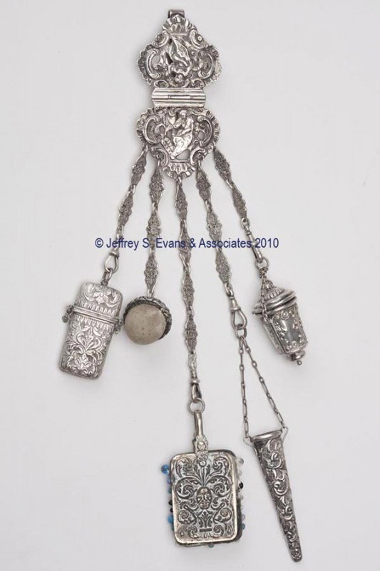 GEORGE UNITE STERLING SILVER NEEDLEWORKING CHATELAIN: GEORGE UNITE STERLING SILVER NEEDLEWORKING CHATELAINE, solid clip attached to a hinged plaque heavily embossed with scrolls and female figures, suspending five chains and five near-matching patterned 