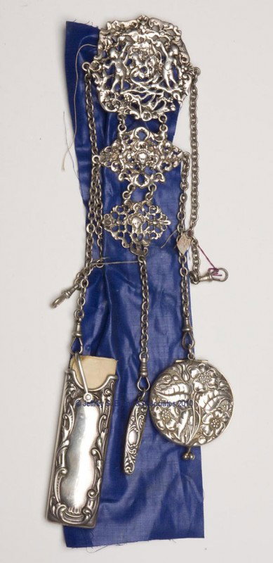 ENGLISH KING AND SON SILVER DANCE CHATELAINE: ENGLISH KING AND SON SILVER DANCE CHATELAINE, solid clip attached to an embossed plaque with cherubs and entwining wreaths, suspending five chains and three non-matching appendages, plaque with hallma