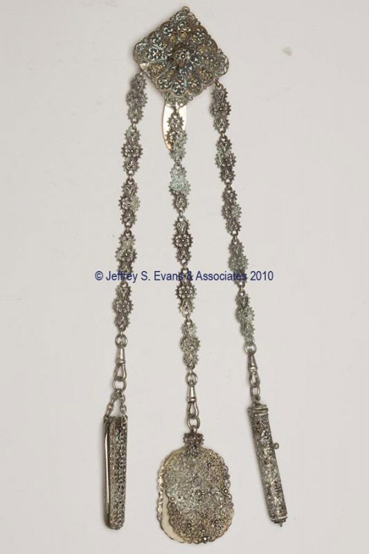 GILT AND FILIGREE METAL DANCE CHATELAINE: GILT AND FILIGREE METAL DANCE CHATELAINE, solid clip and square-form plaque with central applied petal, suspending three filigree chains and near-matching filigree-pattern appendages consisting of a k