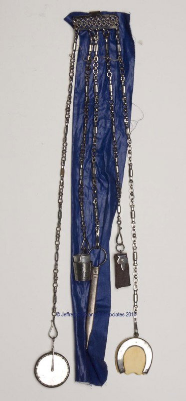 CUT-STEEL NEEDLEWORKING CHATELAINE: CUT-STEEL NEEDLEWORKING CHATELAINE, solid clip with a bar-form plaque featuring crosshatch and bead designs, supporting five chains and five appendages. Appendages consist of a disk-form pin cushion; 