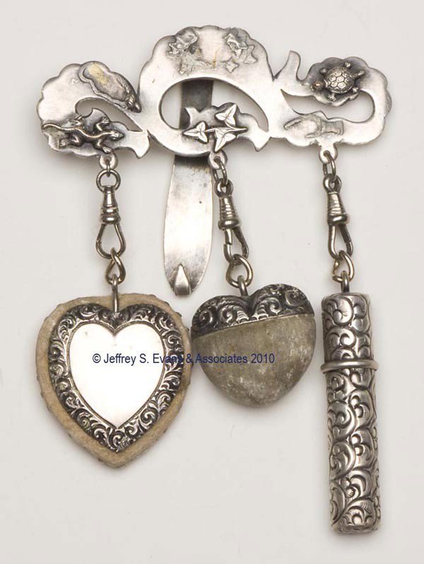 SILVER-PLATED NEEDLEWORKING CHATELAINE: SILVER-PLATED NEEDLEWORKING CHATELAINE, solid clip and plaque with applied figural decoration depicting a lizard, turtle, and ivy, suspending three near-matching heavily embossed needleworking tools c