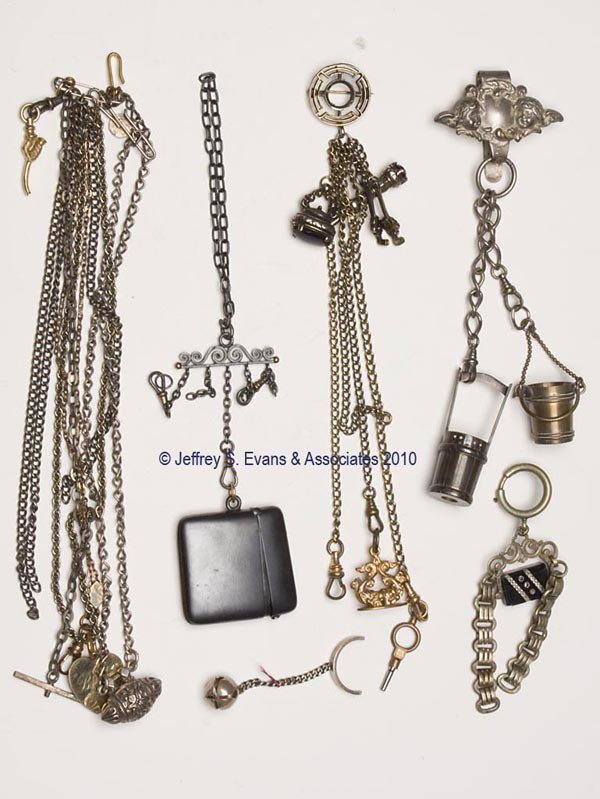 VARIOUS METAL CHATELAINE ACCESSORIES, LOT OF SIX: VARIOUS METAL CHATELAINE ACCESSORIES, LOT OF SIX, including a brooch chatelaine suspending eight chains and appendages consisting of four charms, each with an amethyst colored stone, a seal, and a wat