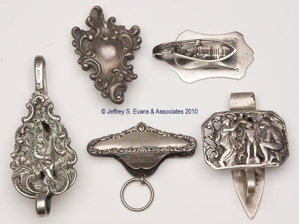 VARIOUS SILVER CHATELAINE CLIPS, LOT OF FIVE: VARIOUS SILVER CHATELAINE CLIPS, LOT OF FIVE, consisting of a figural emperor embossed example with Dutch hallmarks; an English Grey & Co. example with three figures on plaque; a Washington, DC souven