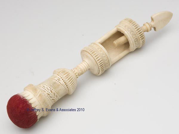 CARVED IVORY SEWING CLAMP WITH PIN CUSHION: CARVED IVORY SEWING CLAMP WITH PIN CUSHION, intricately carved with foliage and ribbed bands supporting an original red velvet pin cushion, unthreads to reveal a cylinder-form needle case, lower porti