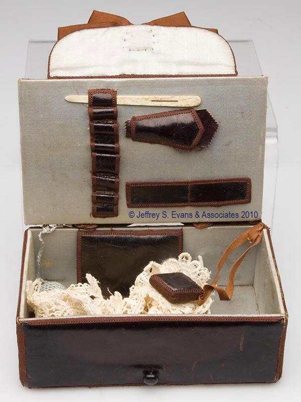 LEATHER COVERED SEWING WORK BOX: LEATHER COVERED SEWING WORK BOX, black leather with brown silk trim and ribbons, hinged lid opens to reveal a green silk lined divided interior containing a built-in brown velvet pin cushion, an attac