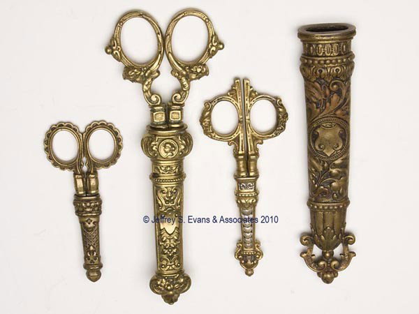 BRASS HEAVILY EMBOSSED SCISSORS WITH SHEATHS, LOT : BRASS HEAVILY EMBOSSED SCISSORS WITH SHEATHS, LOT OF THREE, consisting of an example with cherubs on shanks, blades impressed "Germany"; and two embroidery examples, including a GG Leykauf blade examp