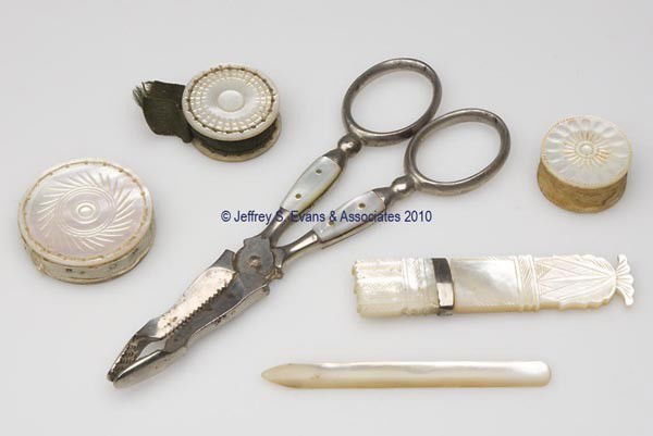 MOTHER-OF-PEARL NEEDLEWORKING TOOLS, LOT OF SIX: MOTHER-OF-PEARL NEEDLEWORKING TOOLS, LOT OF SIX, consisting of two disk-form pin cushions, bodkin, needle case, scissor-form grippers, and a waxer. Mid to late 19th century. Various sizes. Provenance:
