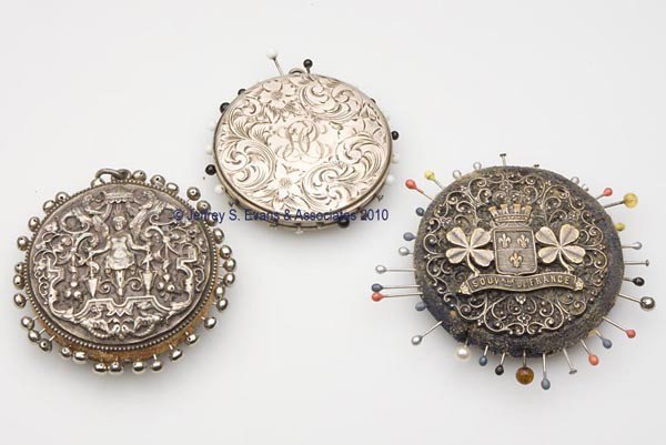 STERLING SILVER AND SILVER-PLATED PIN CUSHIONS, LO: STERLING SILVER AND SILVER-PLATED PIN CUSHIONS, LOT OF THREE, disk forms, consisting of a sterling silver example heavily embossed with sphinx and floral pattern; a silver-plated filigree example with