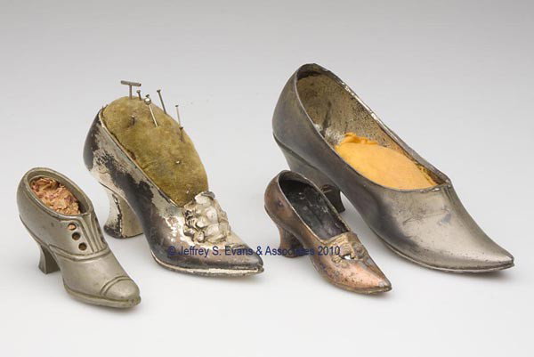 VARIOUS METALS FIGURAL PIN CUSHIONS, LOT OF FOUR: VARIOUS METALS FIGURAL PIN CUSHIONS, LOT OF FOUR, each depicting a high-heel shoe, consisting of three silver-plated examples and a copper-finish spelter example, one with original green velvet pin cu
